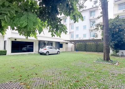 Exterior of an apartment building with a grassy courtyard and parked car