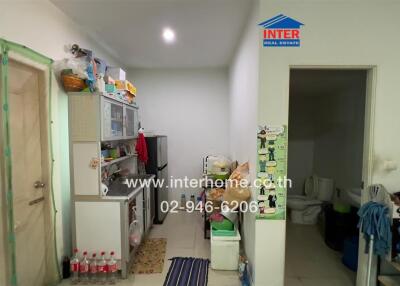 Small kitchen area with shelving, storage, and various household items