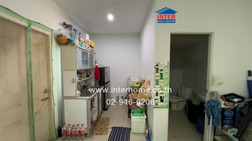 Small kitchen area with shelving, storage, and various household items