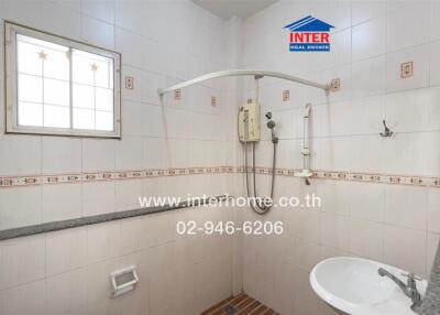 Bathroom with wall tiles, window, sink, and electric shower