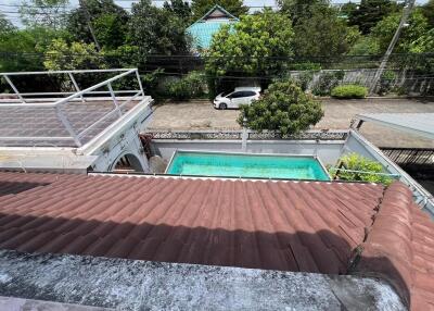 View of a backyard with a swimming pool and surrounding greenery