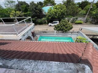 View of a backyard with a swimming pool and surrounding greenery