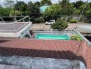 View of a backyard with a swimming pool and surrounding greenery