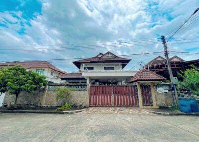 Two-story house with large gate and cloudy sky