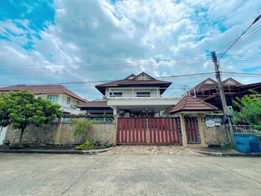 Two-story house with large gate and cloudy sky