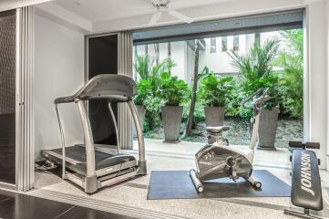 Home gym with treadmill and exercise bike overlooking a garden