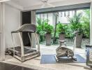 Home gym with treadmill and exercise bike overlooking a garden