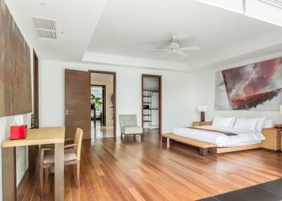 Spacious bedroom with modern decor, wooden flooring, and wall art