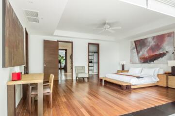 Spacious bedroom with modern decor, wooden flooring, and wall art