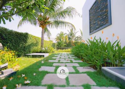 Beautifully landscaped garden with stone pathway, tropical plants, and well-maintained lawn