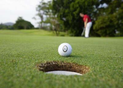 Close-up of a golf ball on the putting green with a golfer in the background