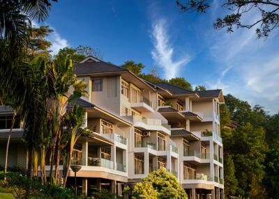 Modern multi-story residential building surrounded by trees