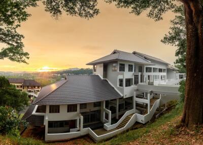 Modern white building surrounded by greenery at sunset