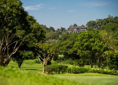 View of a golf course with lush greenery and a building in the distance