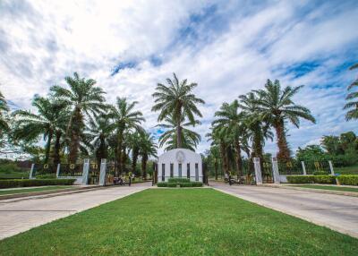 Elegant entrance with palm trees and a white archway under a blue sky