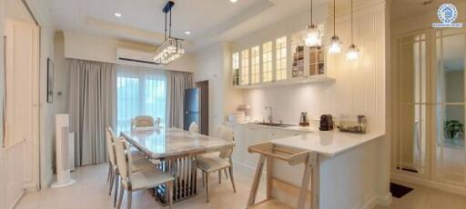 Modern kitchen and dining area with white cabinets and pendant lights