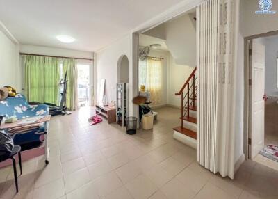 Living room with tiled floor, staircase, and large window with green curtains