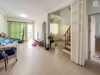 Living room with tiled floor, staircase, and large window with green curtains