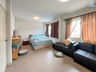 A bright bedroom with a bed, couch, windows, and various furniture.