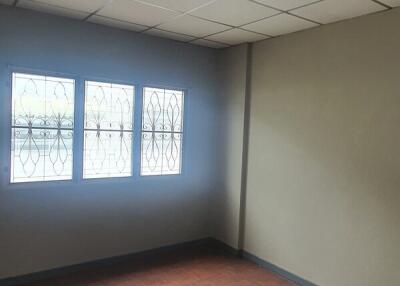 Empty bedroom with ceiling tiles and windows with grille