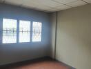 Empty bedroom with ceiling tiles and windows with grille