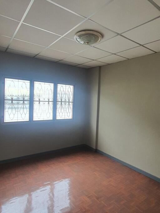 Empty bedroom with ceiling tiles and windows with grille