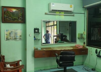 Salon or barbershop with a mirror, chairs, and an air conditioning unit