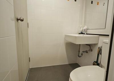 Modern bathroom with a sink, toilet, large mirror, and decorative tiles