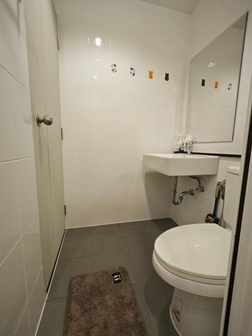 Modern bathroom with a sink, toilet, large mirror, and decorative tiles