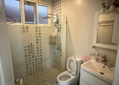 Modern bathroom with glass shower door, sink, toilet, and vanity mirror