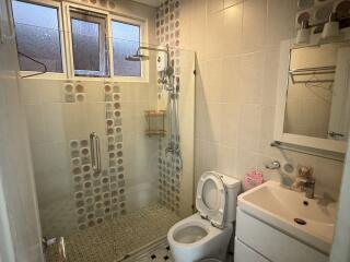 Modern bathroom with glass shower door, sink, toilet, and vanity mirror