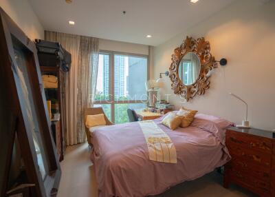 Cozy bedroom with a bed, ornate mirror, and a window with curtains.