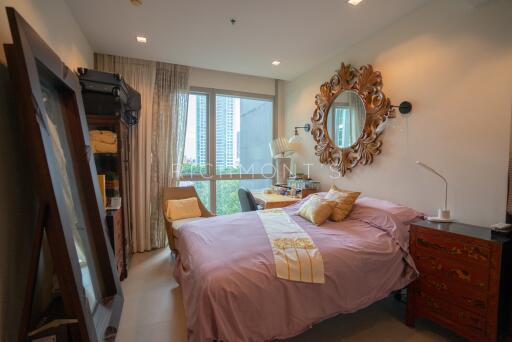 Cozy bedroom with a bed, ornate mirror, and a window with curtains.