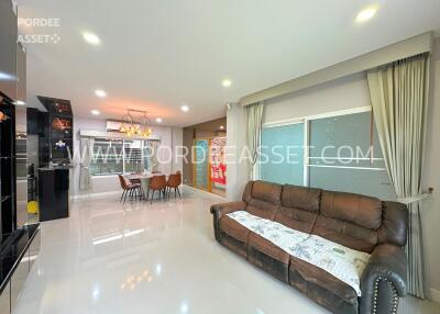 Modern living room with a sofa, chandelier, and adjacent kitchen