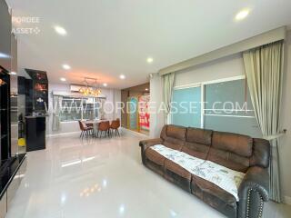 Modern living room with a sofa, chandelier, and adjacent kitchen