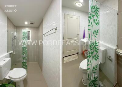 Modern bathroom with white and beige tiles, toilet, shower area with glass partition, and door