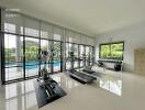 Modern gym with large windows overlooking a pool