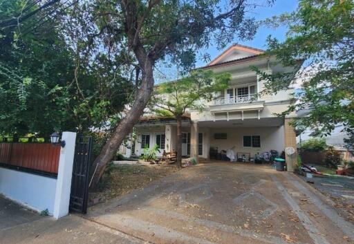 Large two-story house with drive under a tree