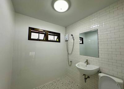 Spacious modern bathroom with white tile walls and fixtures