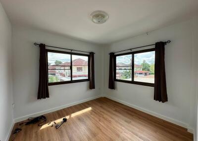 Sunny bedroom with wooden floor and large windows