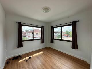 Sunny bedroom with wooden floor and large windows