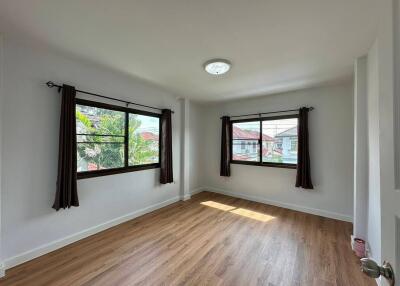 spacious bedroom with wooden floor and large windows