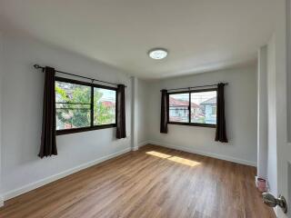 spacious bedroom with wooden floor and large windows