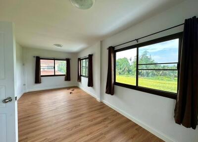 Spacious bedroom with large windows and wooden flooring