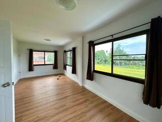 Spacious bedroom with large windows and wooden flooring