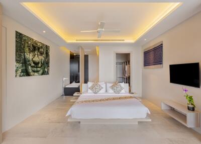 Spacious modern bedroom with ceiling fan, artwork, mounted TV, and minimalist decor