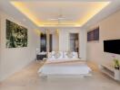 Spacious modern bedroom with ceiling fan, artwork, mounted TV, and minimalist decor