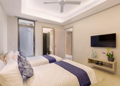 Modern bedroom with two single beds, ceiling fan, and a wall-mounted TV