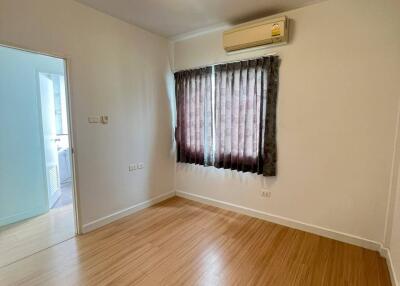 Well-lit empty bedroom with hardwood flooring and window with curtains