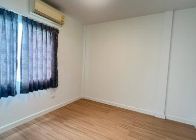 Spacious empty bedroom with wooden floor and curtains.